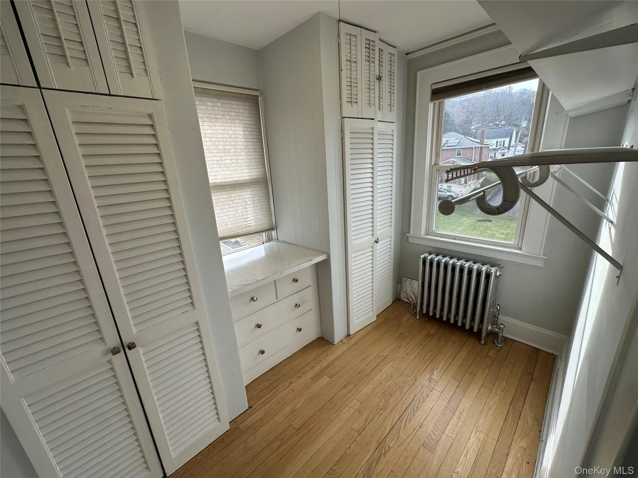 Bedroom featuring two closets, radiator heating unit, and light wood-type flooring Bedroom featuring two closets, radiator heating unit, and light wood-type flooring