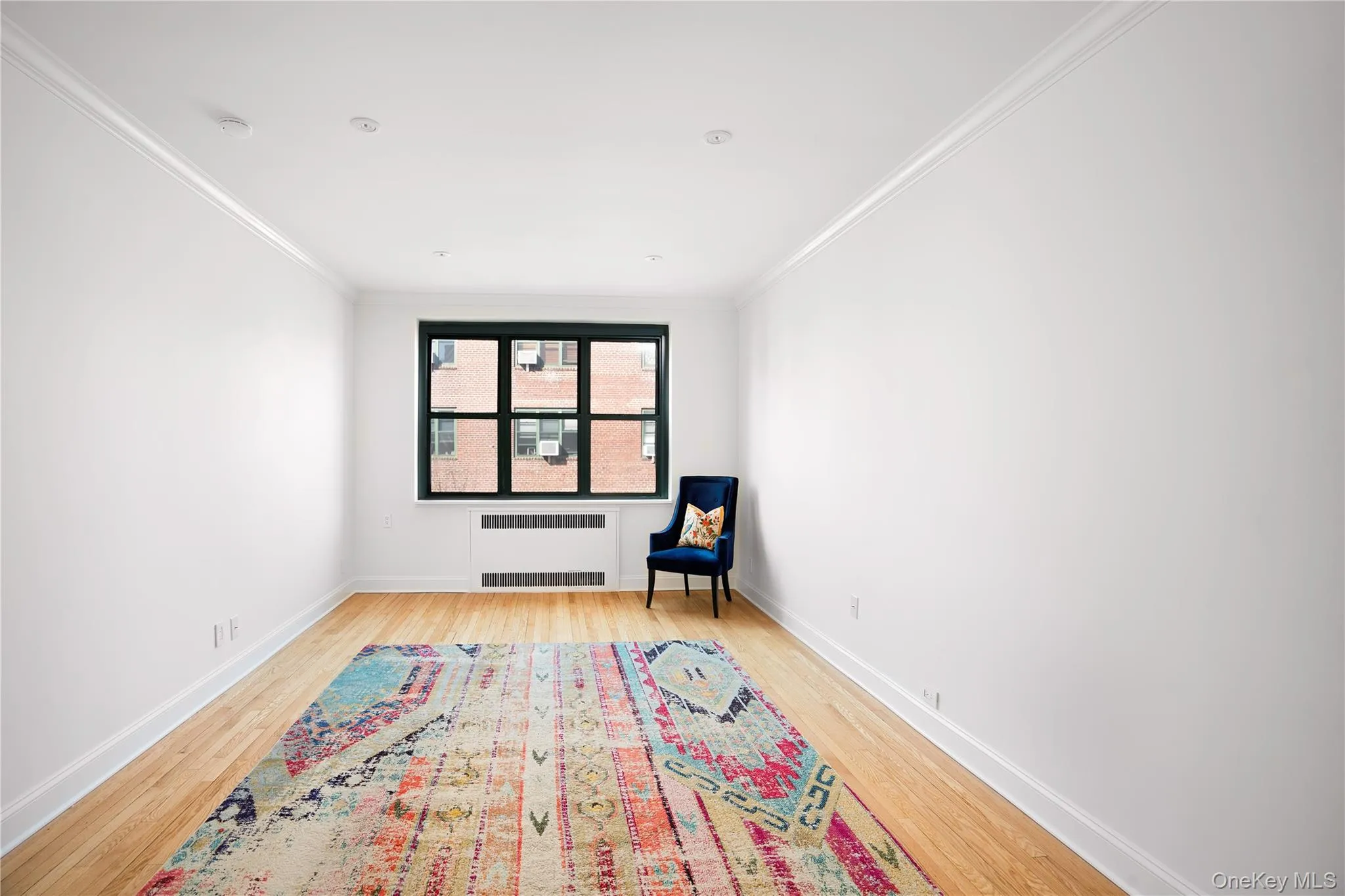 Unfurnished room featuring light wood-style flooring, radiator heating unit, and ornamental molding Unfurnished room featuring light wood-style flooring, radiator heating unit, and ornamental molding
