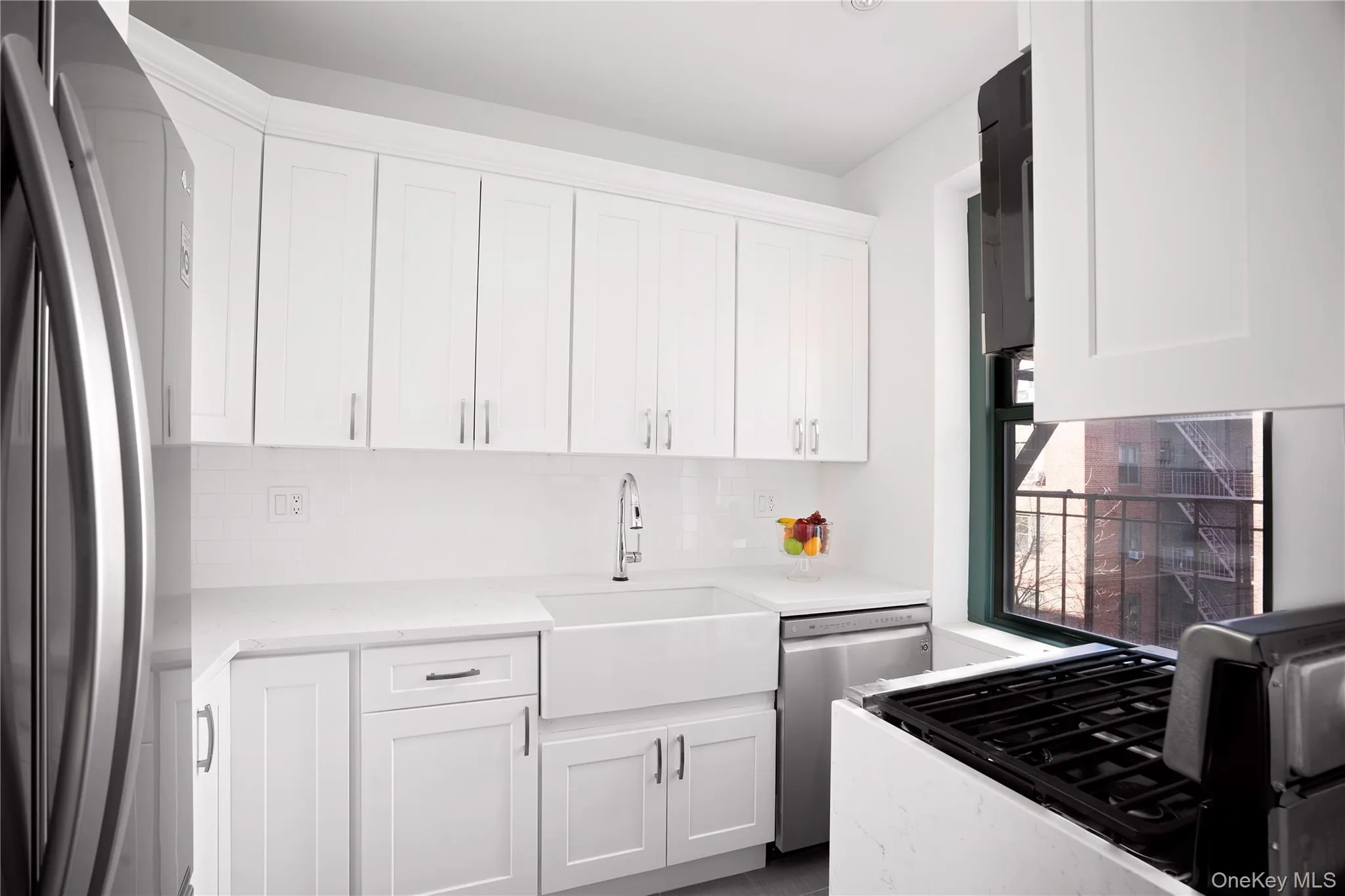 Kitchen featuring stainless steel appliances, white cabinetry, light stone counters, and decorative backsplash Kitchen featuring stainless steel appliances, white cabinetry, light stone counters, and decorative backsplash