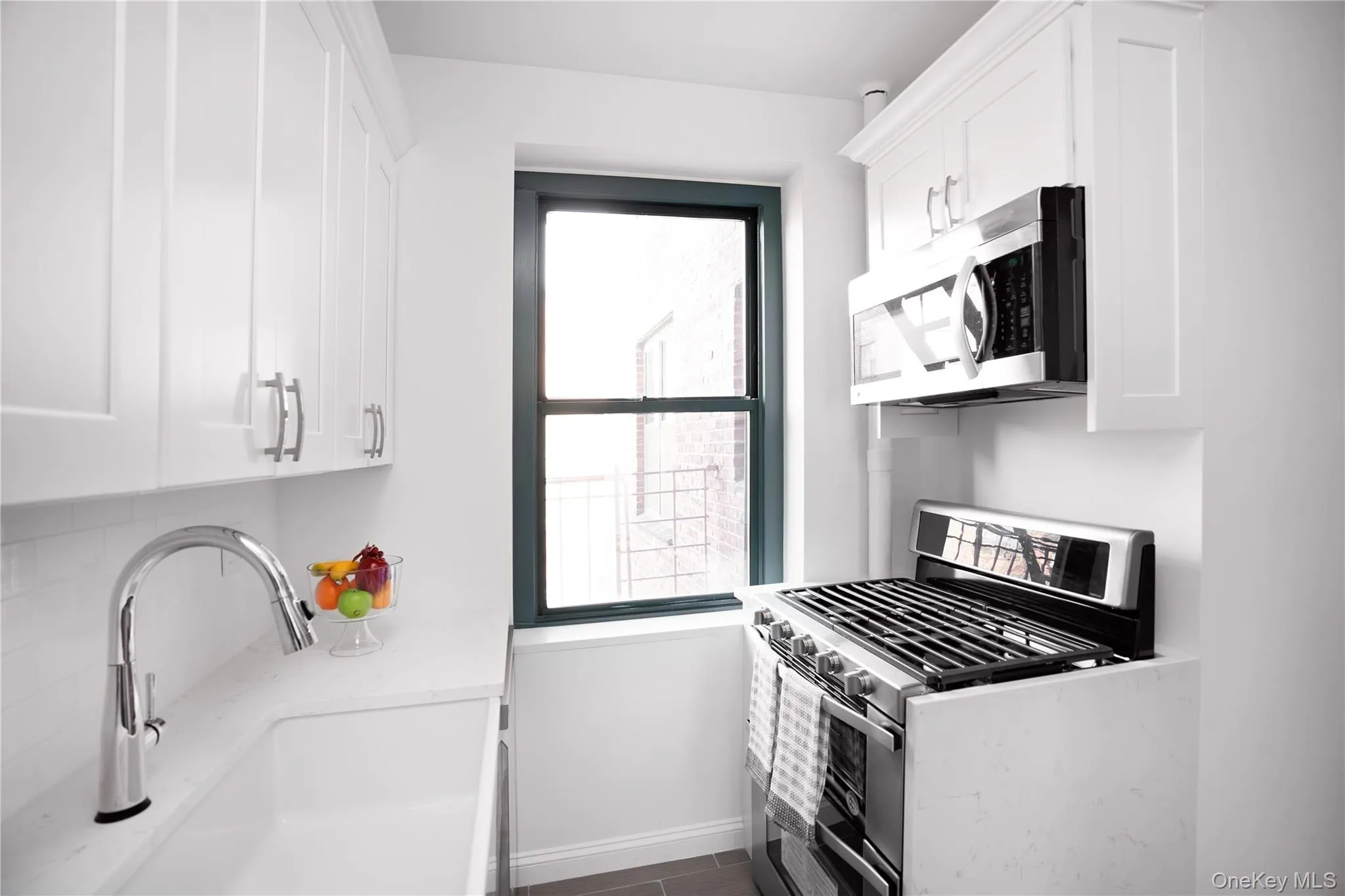 Kitchen with appliances with stainless steel finishes, white cabinetry, and light stone countertops Kitchen with appliances with stainless steel finishes, white cabinetry, and light stone countertops