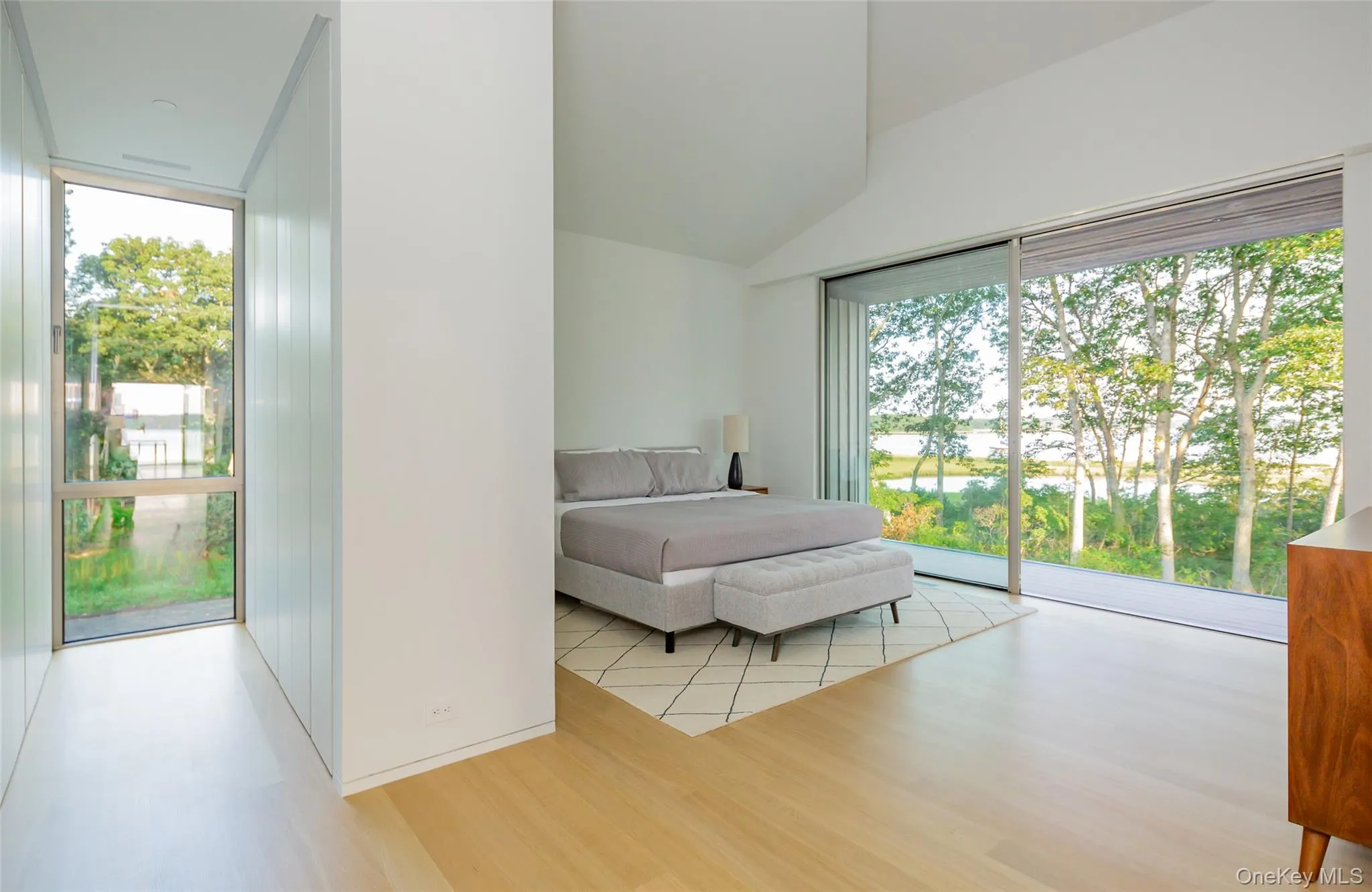 Bedroom featuring light wood-style flooring, access to exterior, and lofted ceiling Bedroom featuring light wood-style flooring, access to exterior, and lofted ceiling