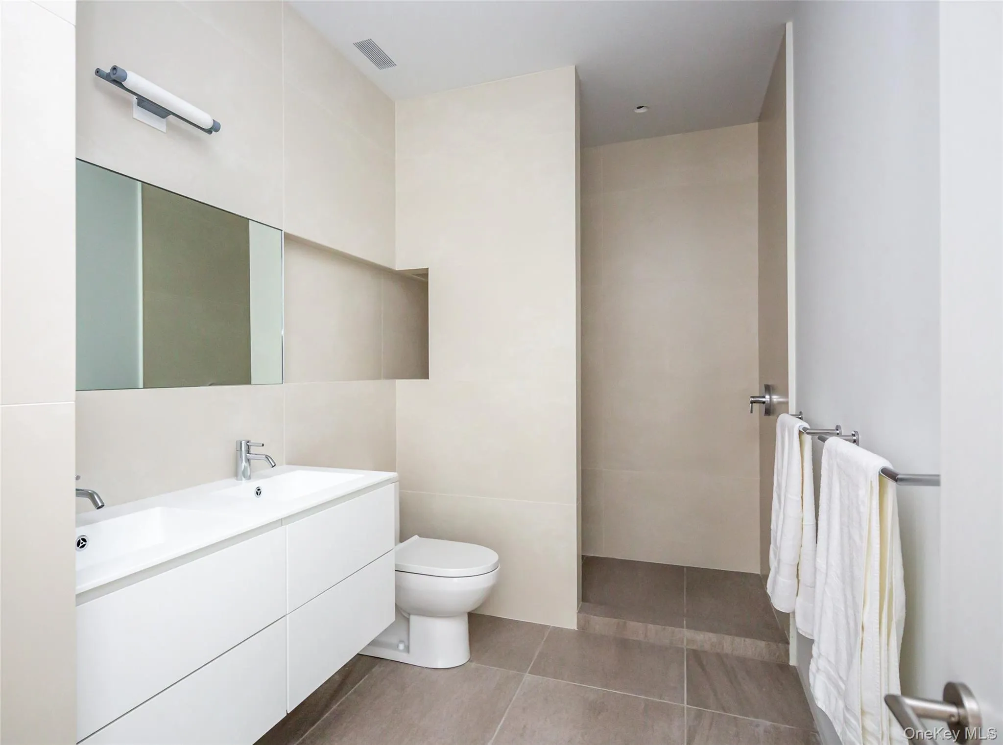 Bathroom with double vanity, tile walls, and a walk in shower Bathroom with double vanity, tile walls, and a walk in shower