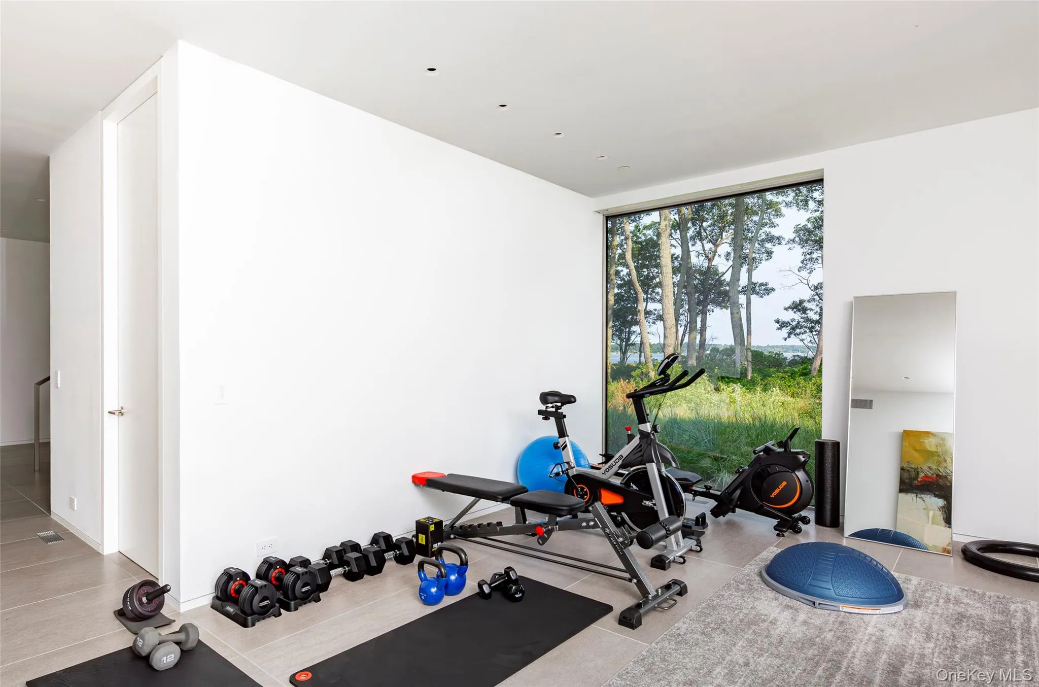 Workout area with a wall of windows and light tile patterned flooring Workout area with a wall of windows and light tile patterned flooring