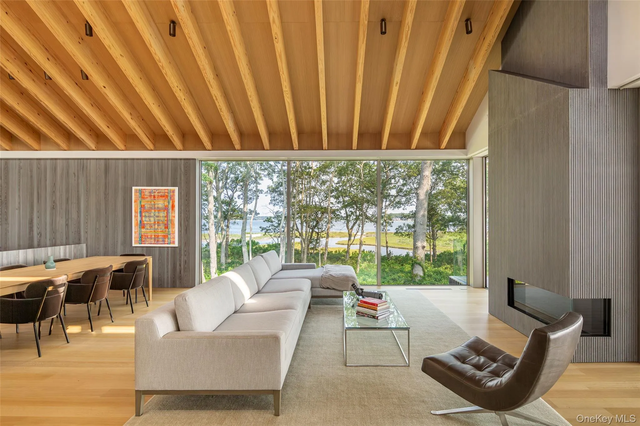 Living area featuring a large fireplace, a water view, light wood-type flooring, and a wood ceiling with exposed beams Living area featuring a large fireplace, a water view, light wood-type flooring, and a wood ceiling with exposed beams