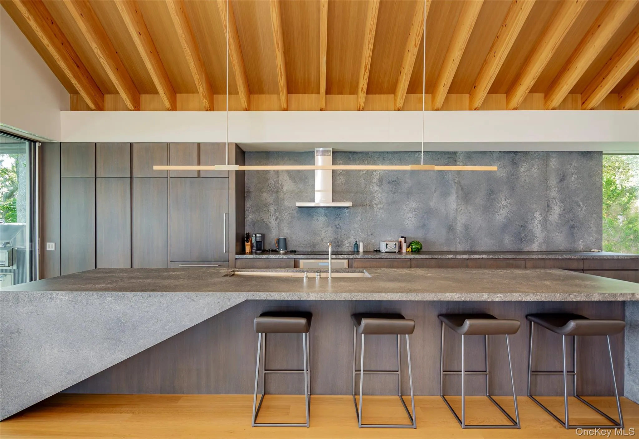 Kitchen with modern cabinets, wall chimney exhaust hood, decorative backsplash, and light stone countertops Kitchen with modern cabinets, wall chimney exhaust hood, decorative backsplash, and light stone countertops