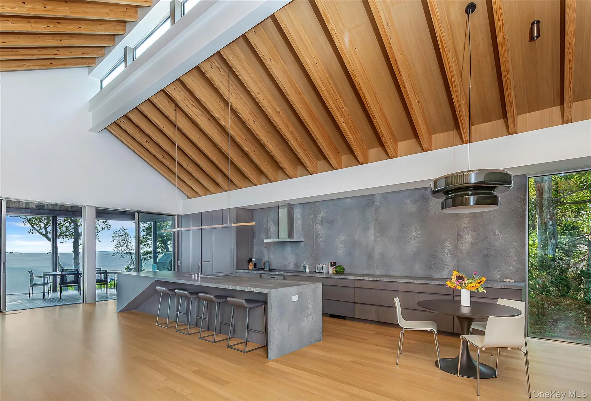 Kitchen with modern cabinets, high vaulted ceiling, a kitchen bar, light stone countertops, and light wood finished floors Kitchen with modern cabinets, high vaulted ceiling, a kitchen bar, light stone countertops, and light wood finished floors