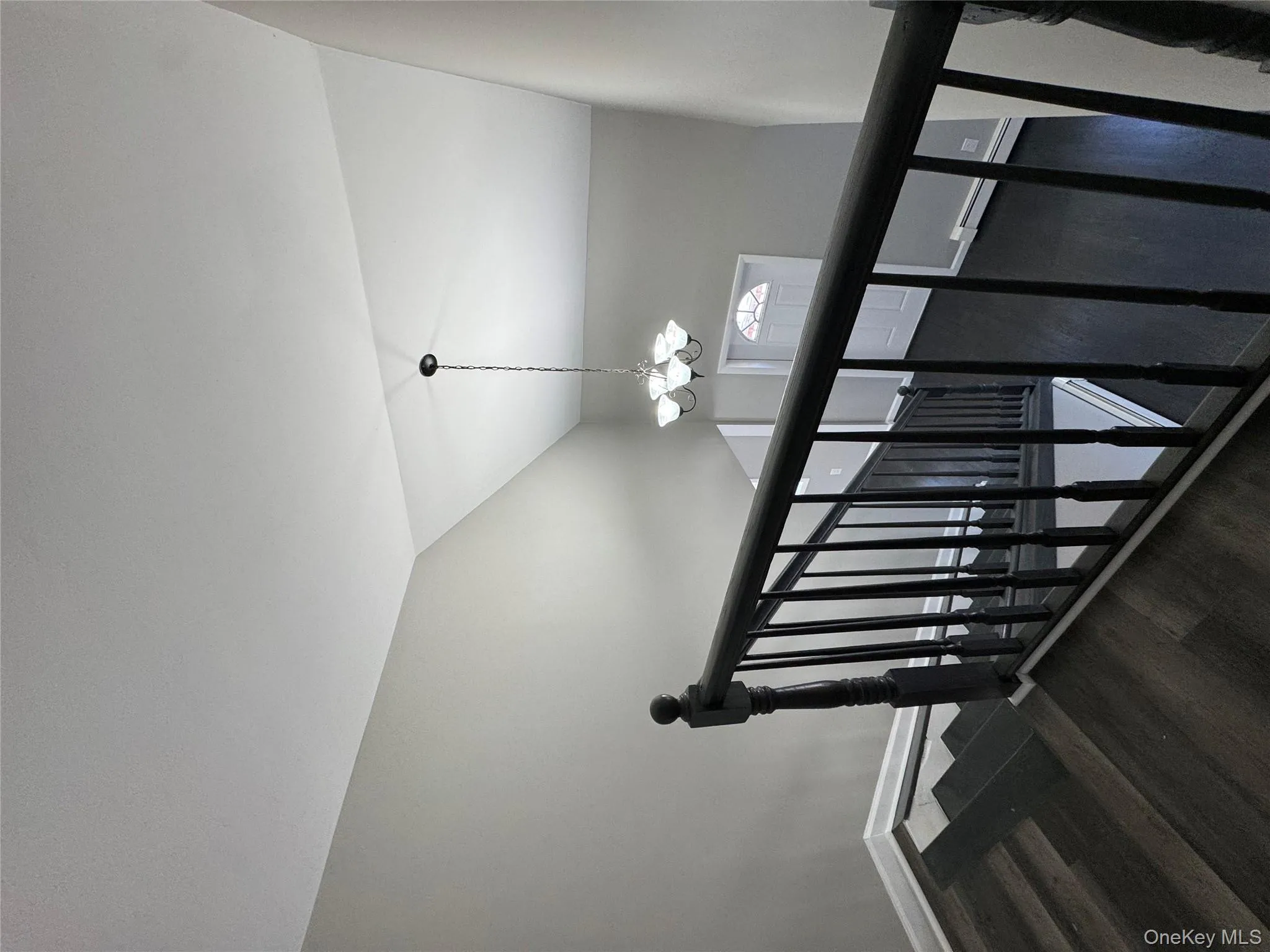 Stairway with vaulted ceiling, wood-type flooring, a baseboard heating unit, and an inviting chandelier Stairway with vaulted ceiling, wood-type flooring, a baseboard heating unit, and an inviting chandelier