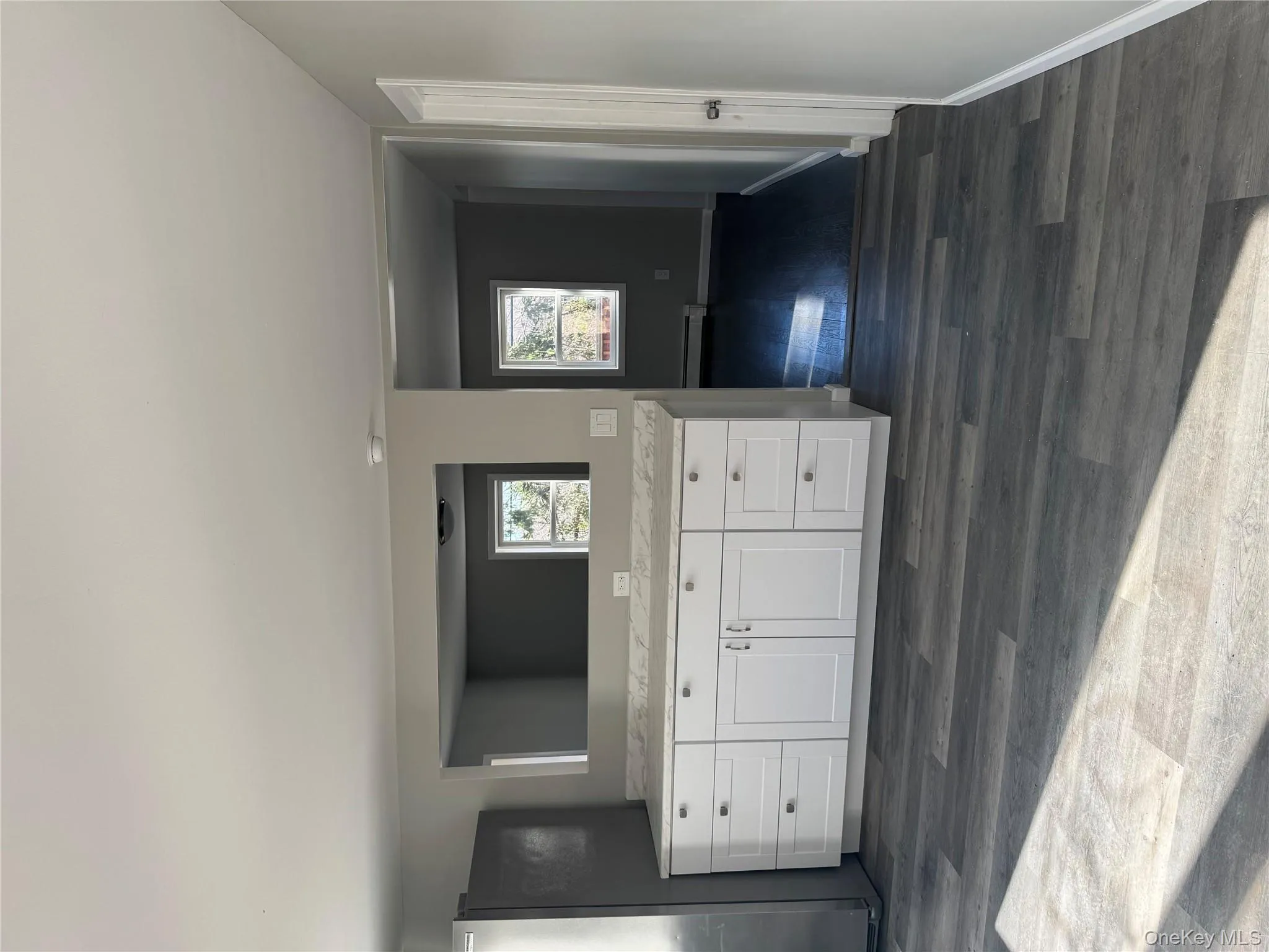 Kitchen featuring dark hardwood / wood-style flooring, white cabinetry, fridge, and a baseboard heating unit Kitchen featuring dark hardwood / wood-style flooring, white cabinetry, fridge, and a baseboard heating unit
