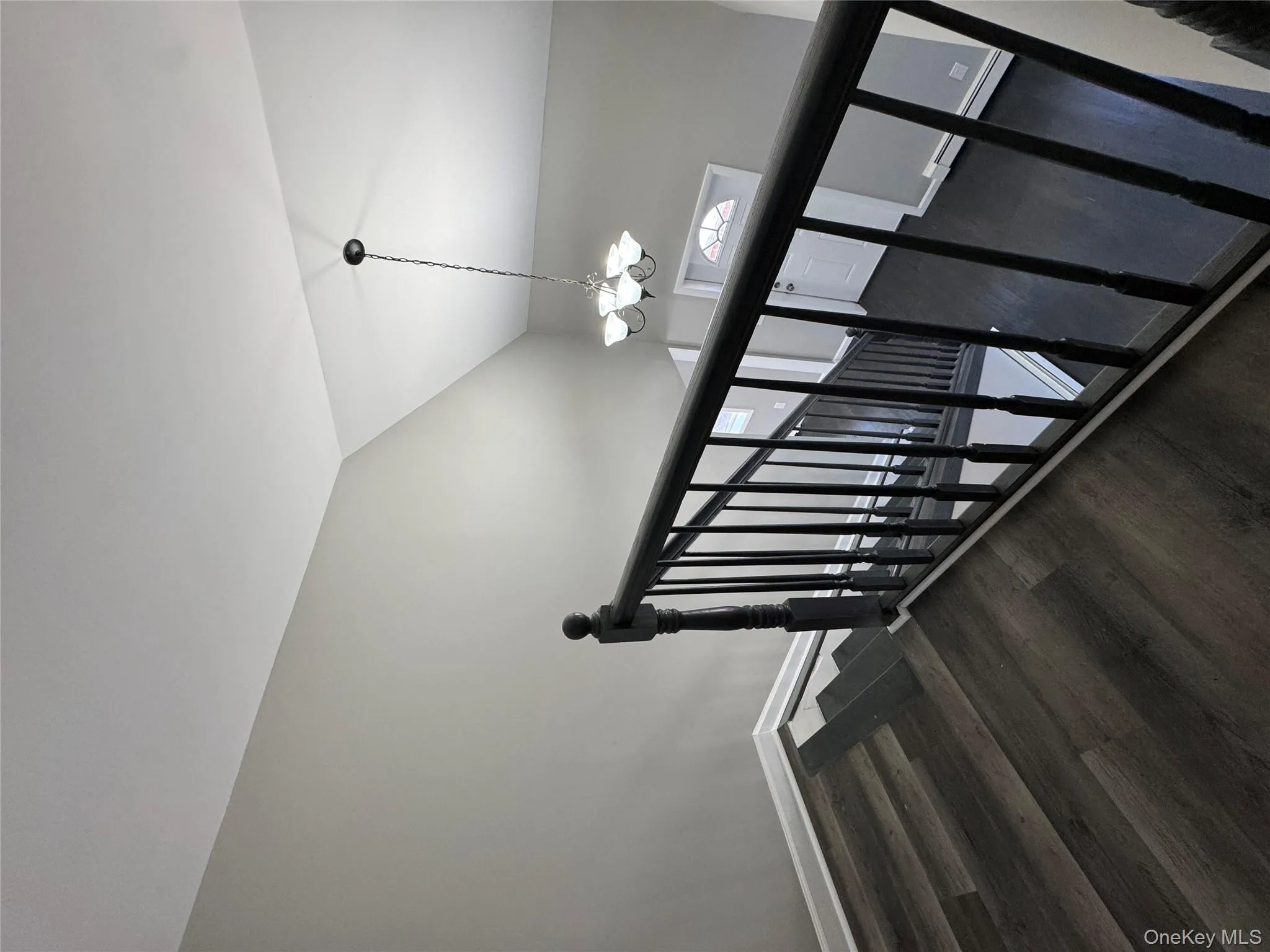Staircase with hardwood / wood-style floors, a notable chandelier, lofted ceiling, and a baseboard heating unit Staircase with hardwood / wood-style floors, a notable chandelier, lofted ceiling, and a baseboard heating unit