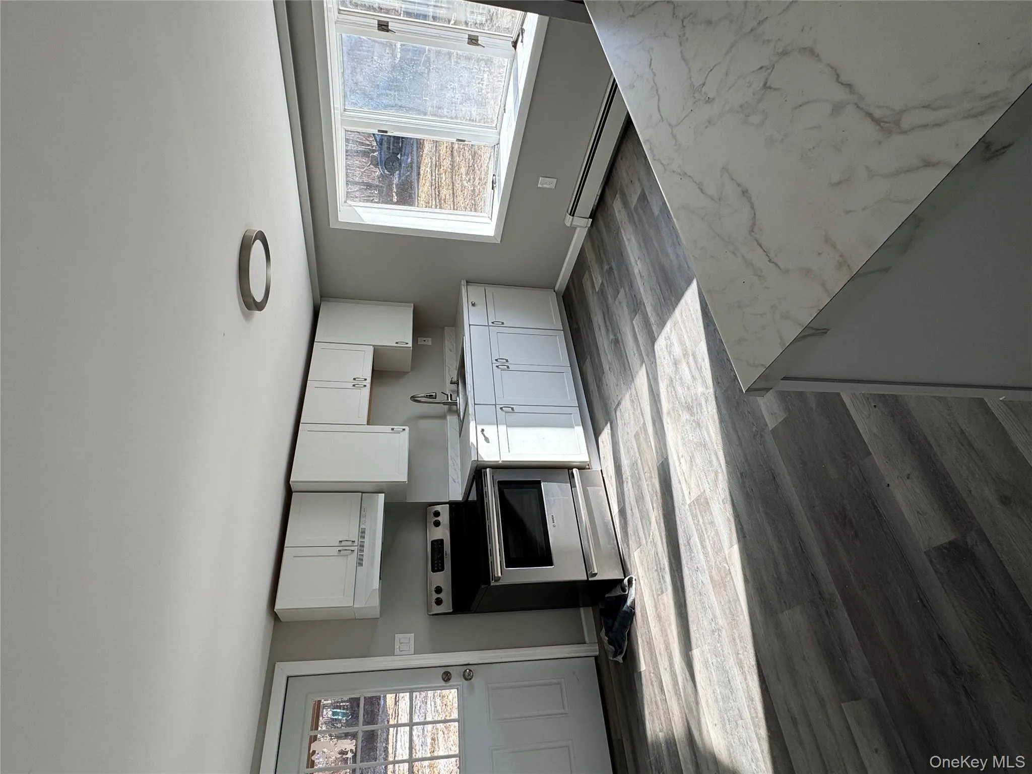 Kitchen with range, wood-type flooring, baseboard heating, range hood, and white cabinetry Kitchen with range, wood-type flooring, baseboard heating, range hood, and white cabinetry