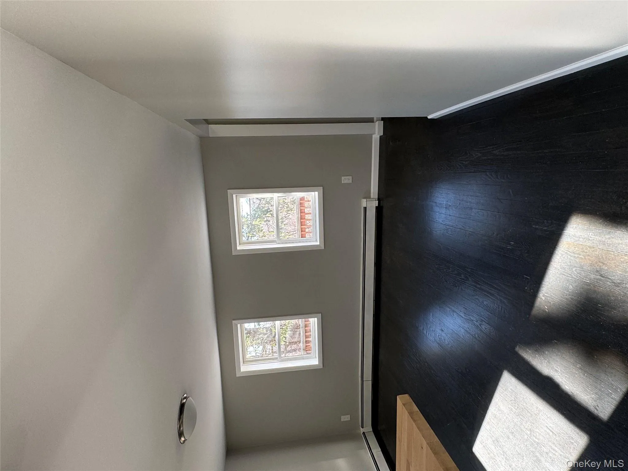 Spare room featuring baseboard heating, dark hardwood / wood-style flooring, and plenty of natural light Spare room featuring baseboard heating, dark hardwood / wood-style flooring, and plenty of natural light