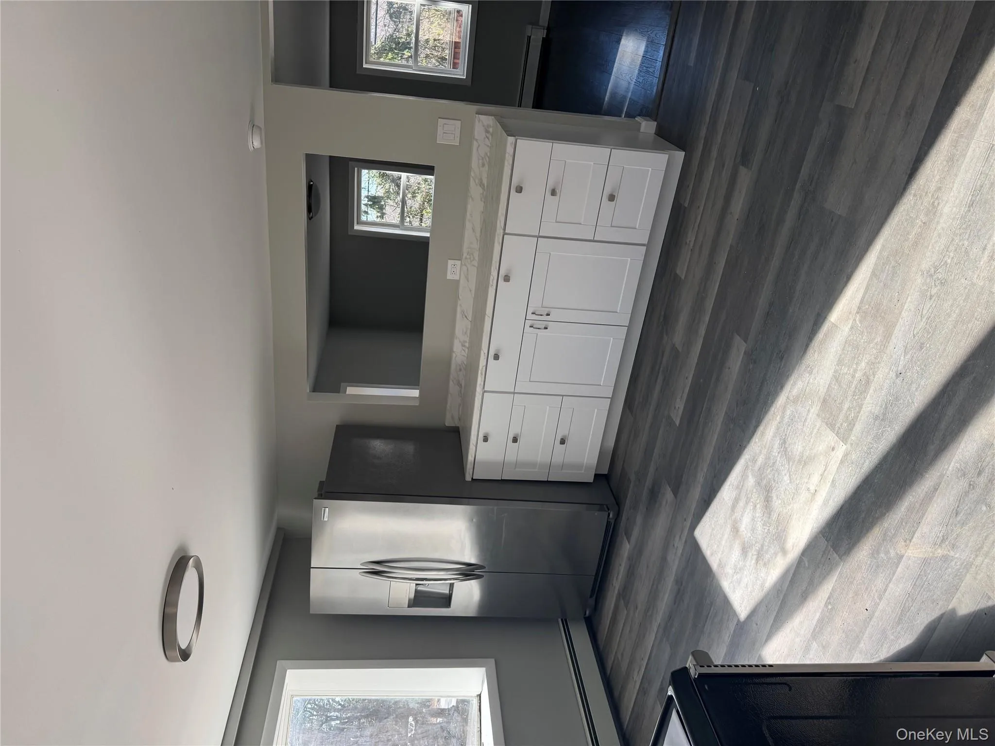 Kitchen with white cabinets, dark hardwood / wood-style flooring, fridge, and a baseboard heating unit Kitchen with white cabinets, dark hardwood / wood-style flooring, fridge, and a baseboard heating unit