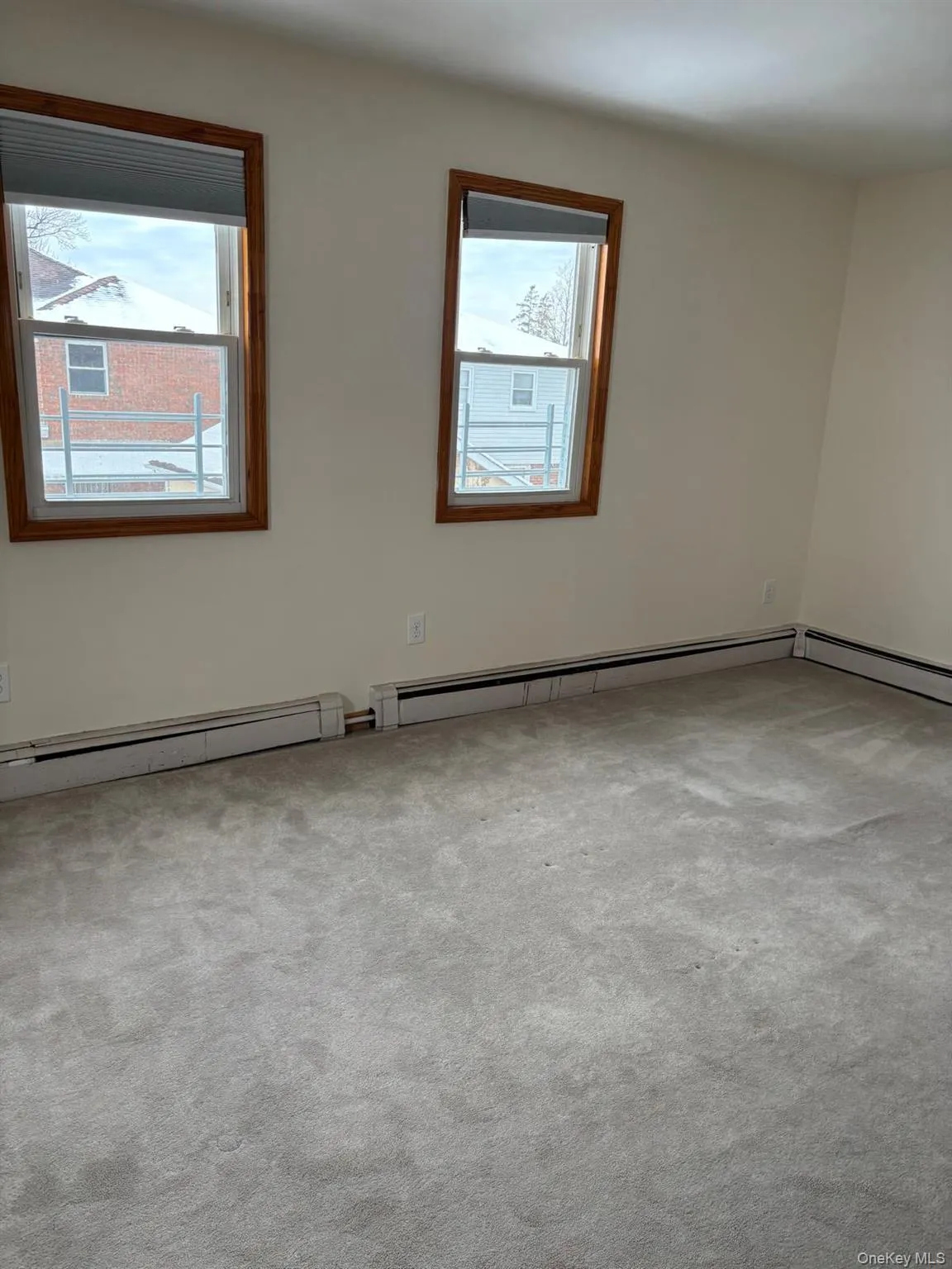 Empty room with light carpet, a baseboard heating unit, and plenty of natural light Empty room with light carpet, a baseboard heating unit, and plenty of natural light