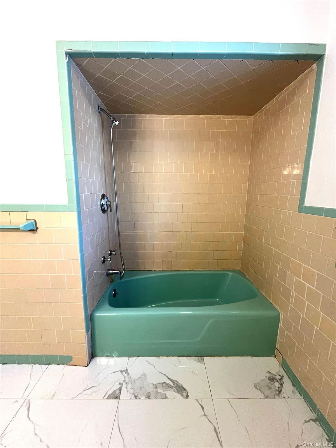 Full bath with tile walls, shower / washtub combination, wainscoting, and marble look tile flooring Full bath with tile walls, shower / washtub combination, wainscoting, and marble look tile flooring