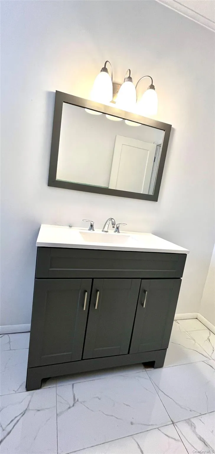Bathroom featuring vanity and light marble finish floors Bathroom featuring vanity and light marble finish floors