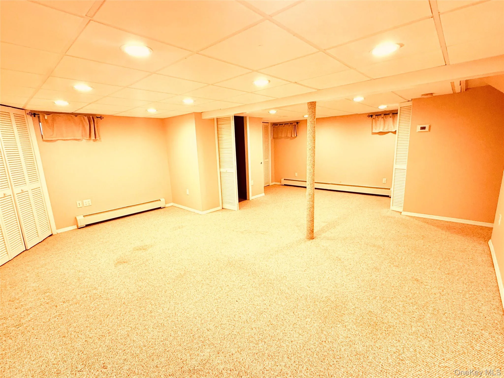 Finished basement with a baseboard radiator, carpet flooring, recessed lighting, and a drop ceiling Finished basement with a baseboard radiator, carpet flooring, recessed lighting, and a drop ceiling