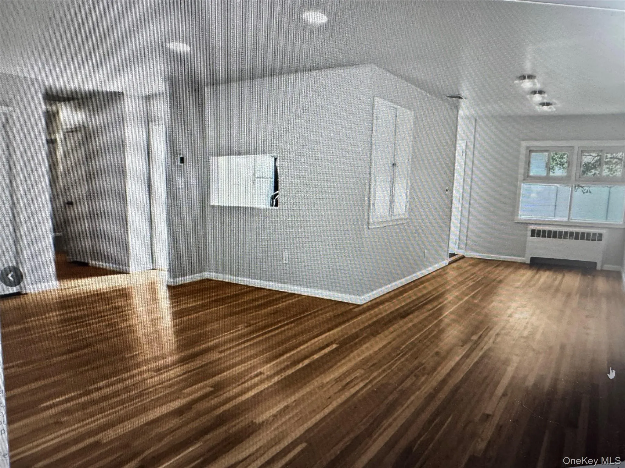 Spare room featuring radiator heating unit and dark wood-style floors Spare room featuring radiator heating unit and dark wood-style floors