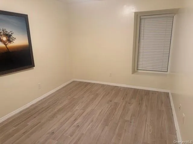 Empty room featuring wood finished floors and baseboards Empty room featuring wood finished floors and baseboards