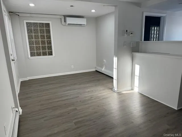 Living/Dinning room featuring dark reclaimed wood floors, baseboard heating, a baseboard radiator, an AC wall unit, and recessed lighting Living/Dinning room featuring dark reclaimed wood floors, baseboard heating, a baseboard radiator, an AC wall unit, and recessed lighting