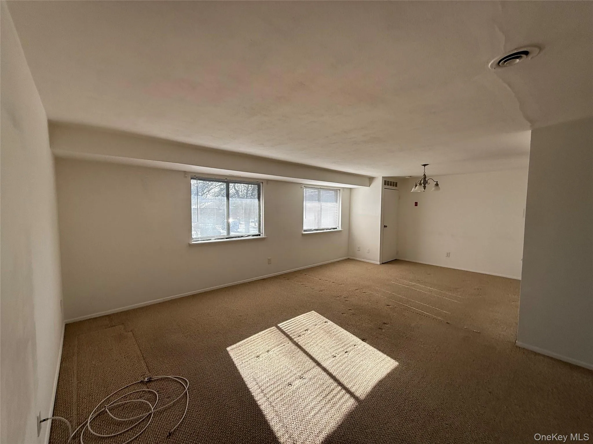Carpeted spare room featuring a chandelier and baseboards Carpeted spare room featuring a chandelier and baseboards