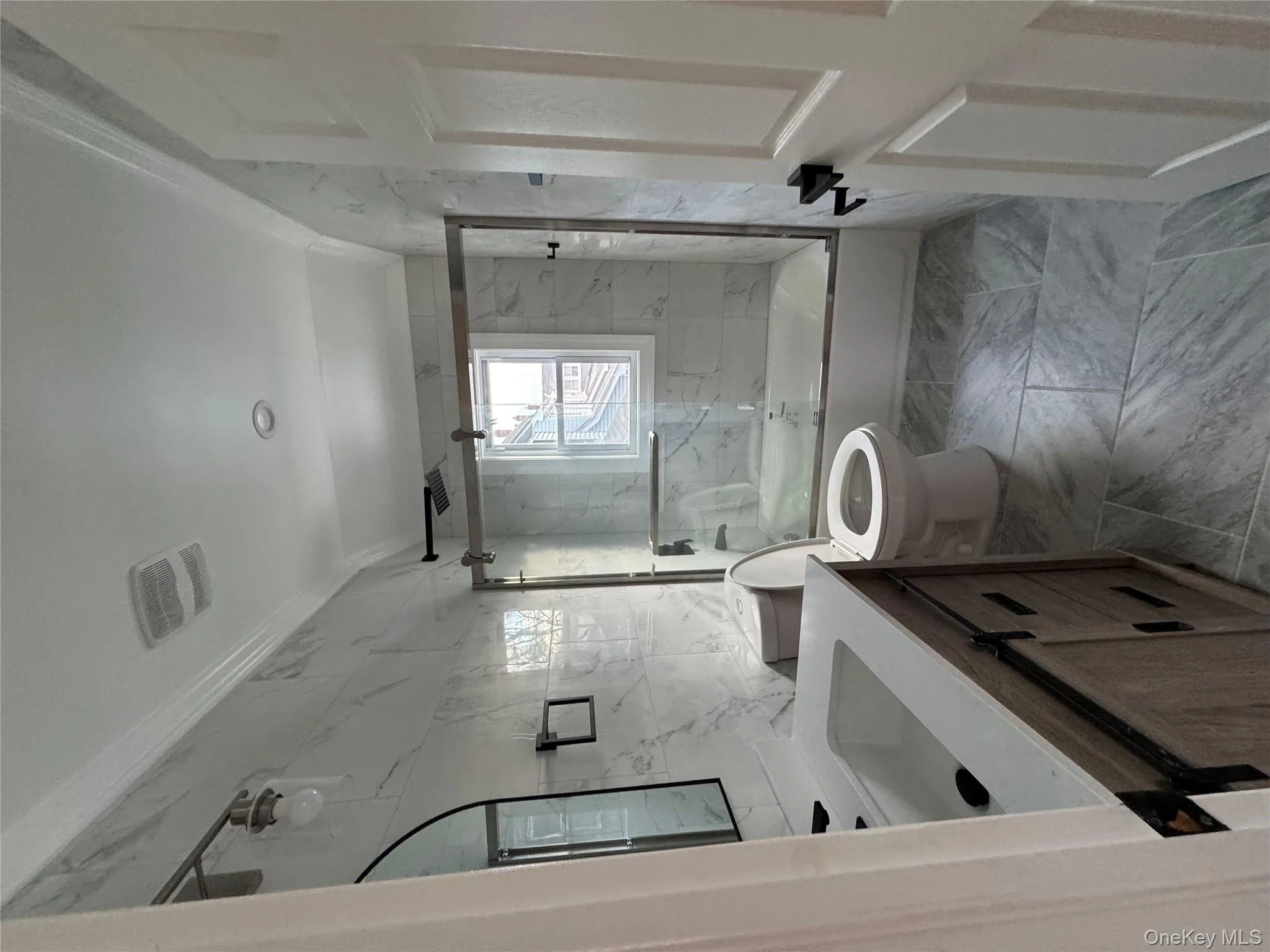 Full bathroom featuring ornamental molding, a combined bath / shower with marble appearance, vanity, light marble finish flooring, and tile walls Full bathroom featuring ornamental molding, a combined bath / shower with marble appearance, vanity, light marble finish flooring, and tile walls