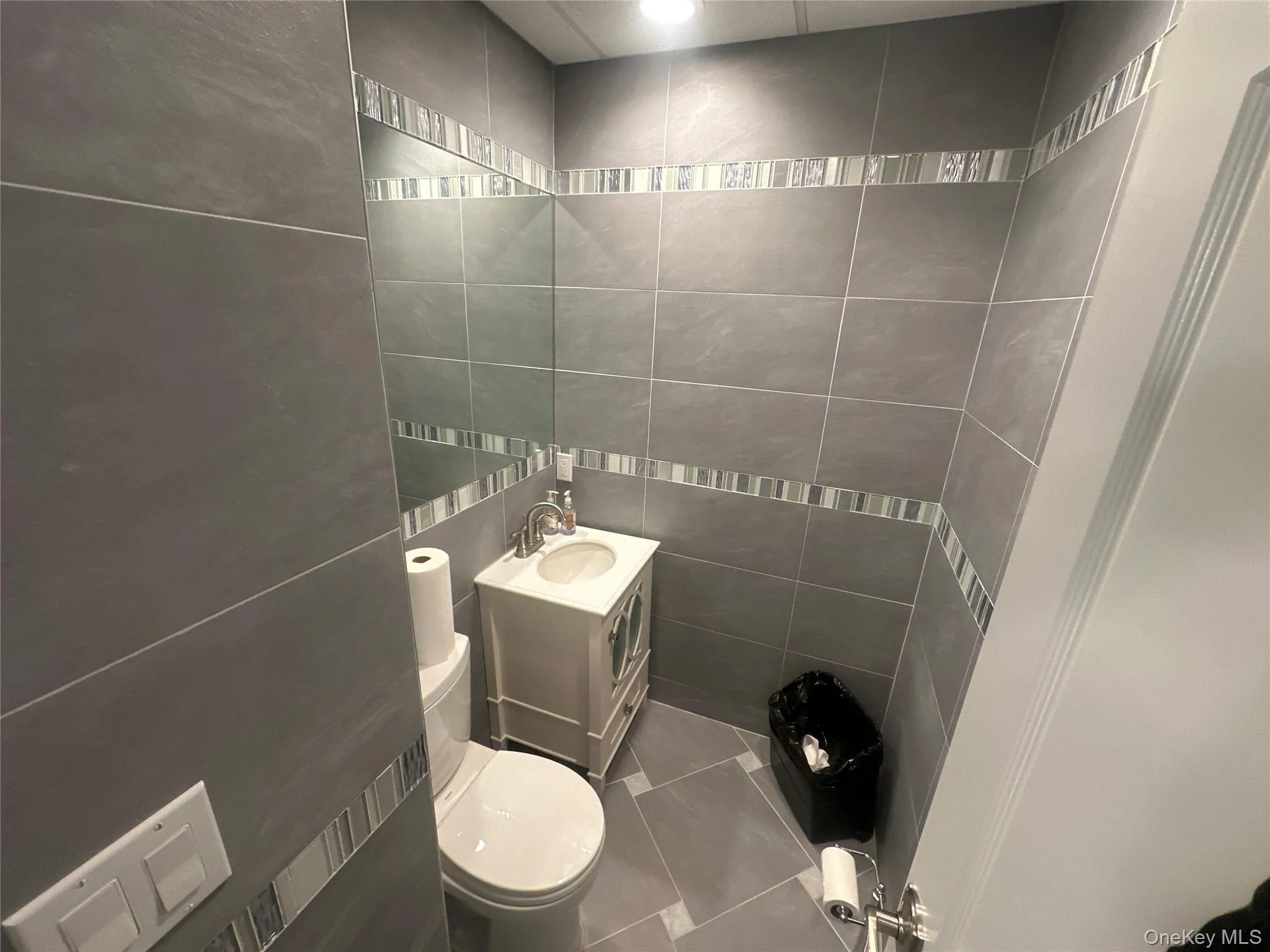 Bathroom featuring vanity, tile walls, and tile patterned flooring Bathroom featuring vanity, tile walls, and tile patterned flooring