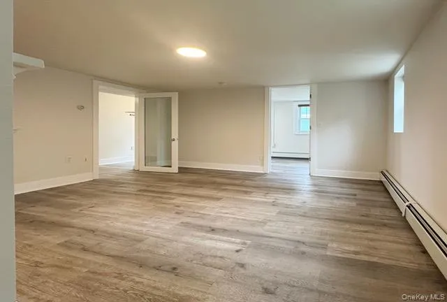 Unfurnished room featuring a baseboard heating unit and light wood-style floors Unfurnished room featuring a baseboard heating unit and light wood-style floors