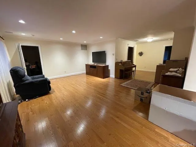Living area featuring crown molding, recessed lighting, and light wood-style flooring Living area featuring crown molding, recessed lighting, and light wood-style flooring