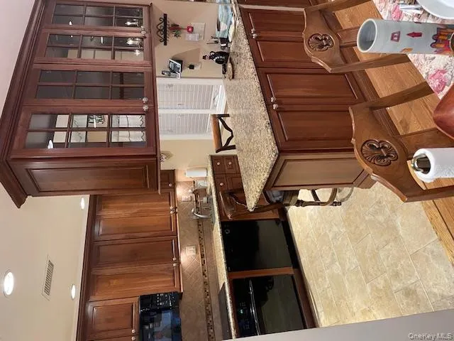 Kitchen with glass insert cabinets, oven, light stone countertops, dishwashing machine, and a breakfast bar area Kitchen with glass insert cabinets, oven, light stone countertops, dishwashing machine, and a breakfast bar area