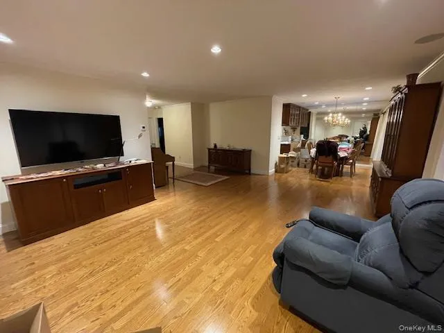Living room featuring light wood-style flooring, recessed lighting, and a big screen tv Living room featuring light wood-style flooring, recessed lighting, and a big screen tv