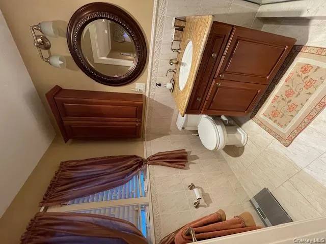 Bathroom with vanity, tile walls, a wainscoted wall, and light tile patterned floors Bathroom with vanity, tile walls, a wainscoted wall, and light tile patterned floors