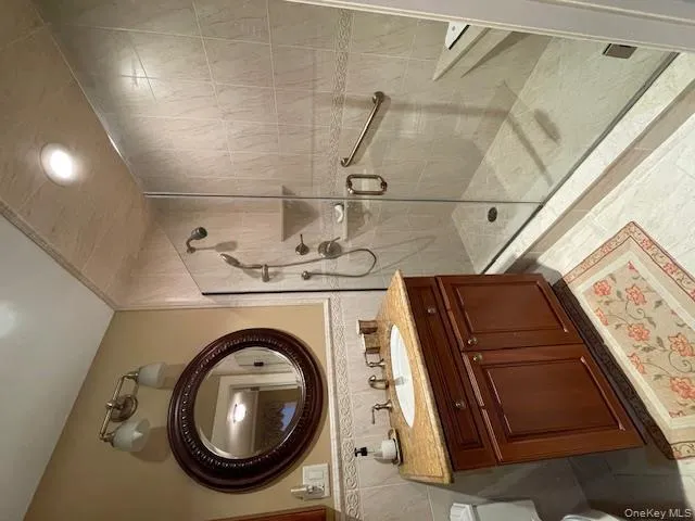 Full bathroom with vanity, a stall shower, tile walls, wainscoting, and recessed lighting Full bathroom with vanity, a stall shower, tile walls, wainscoting, and recessed lighting