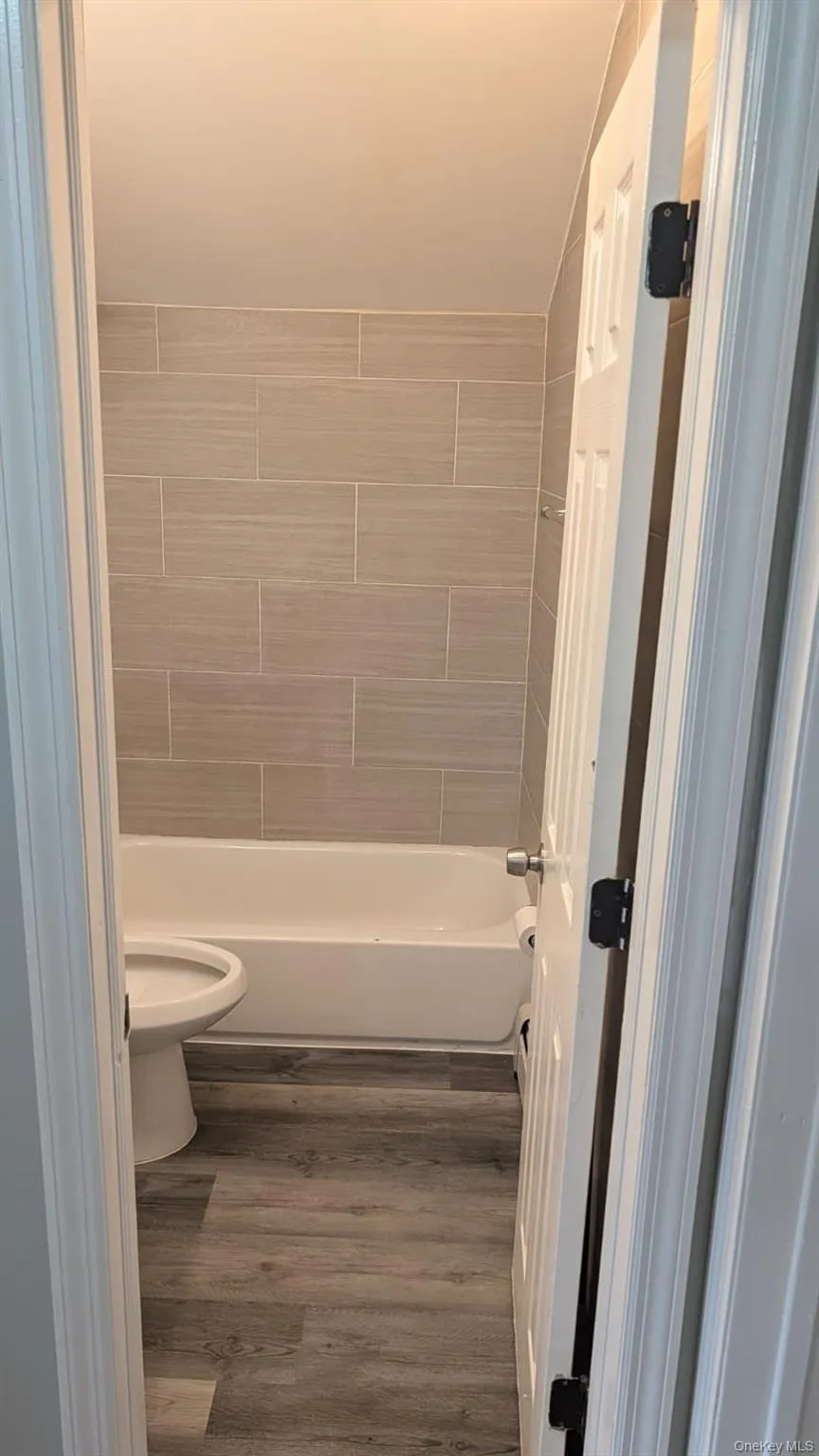 Full bath with dark wood-style flooring, bathtub / shower combination, and lofted ceiling Full bath with dark wood-style flooring, bathtub / shower combination, and lofted ceiling