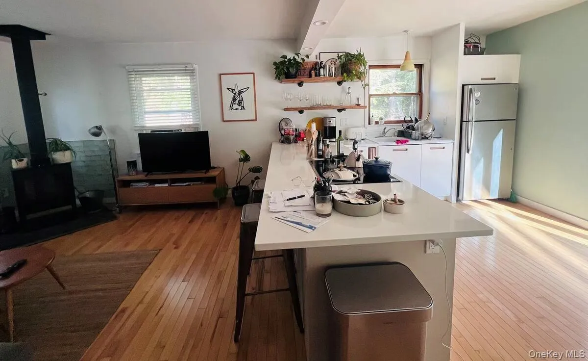 Kitchen featuring a wood stove, a kitchen breakfast bar, light countertops, freestanding refrigerator, and a peninsula Kitchen featuring a wood stove, a kitchen breakfast bar, light countertops, freestanding refrigerator, and a peninsula