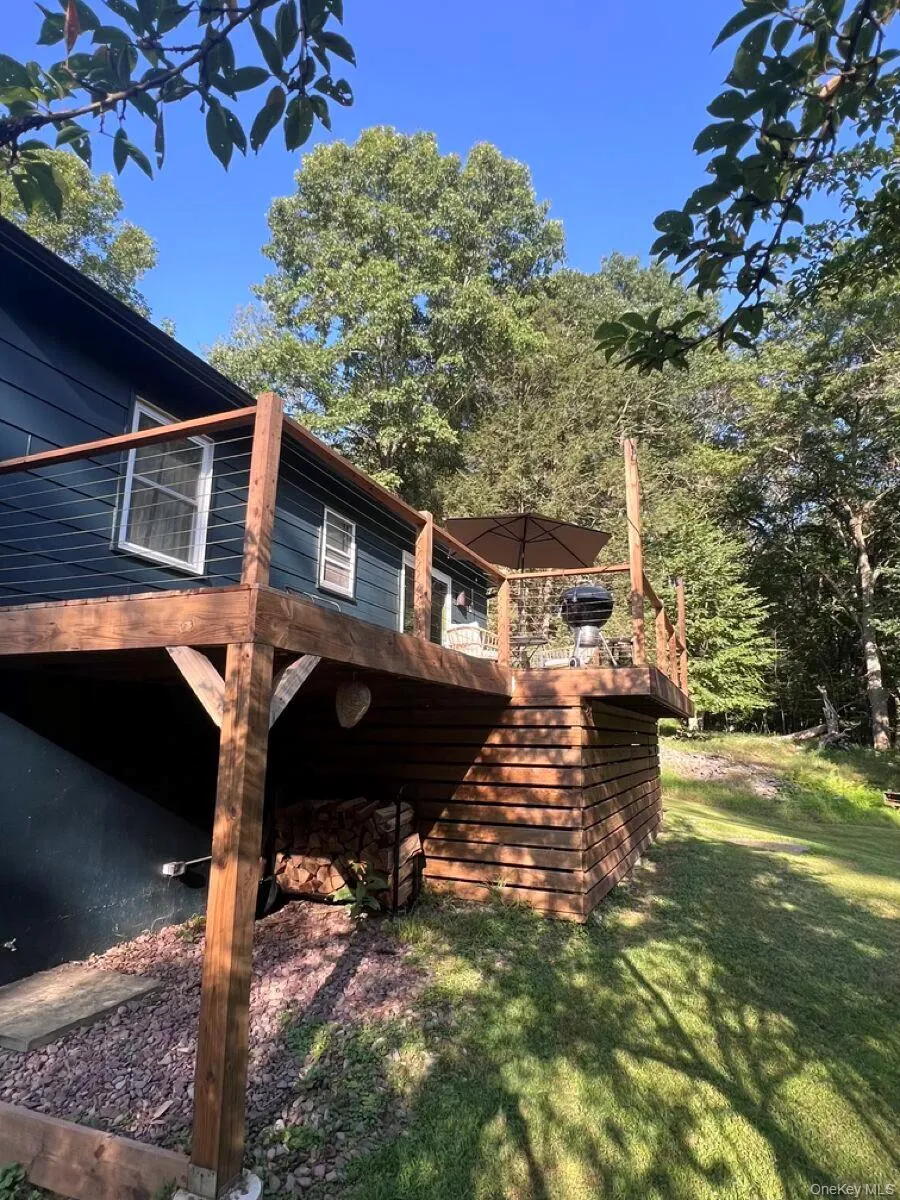 View of side of property with a lawn and a wooden deck View of side of property with a lawn and a wooden deck