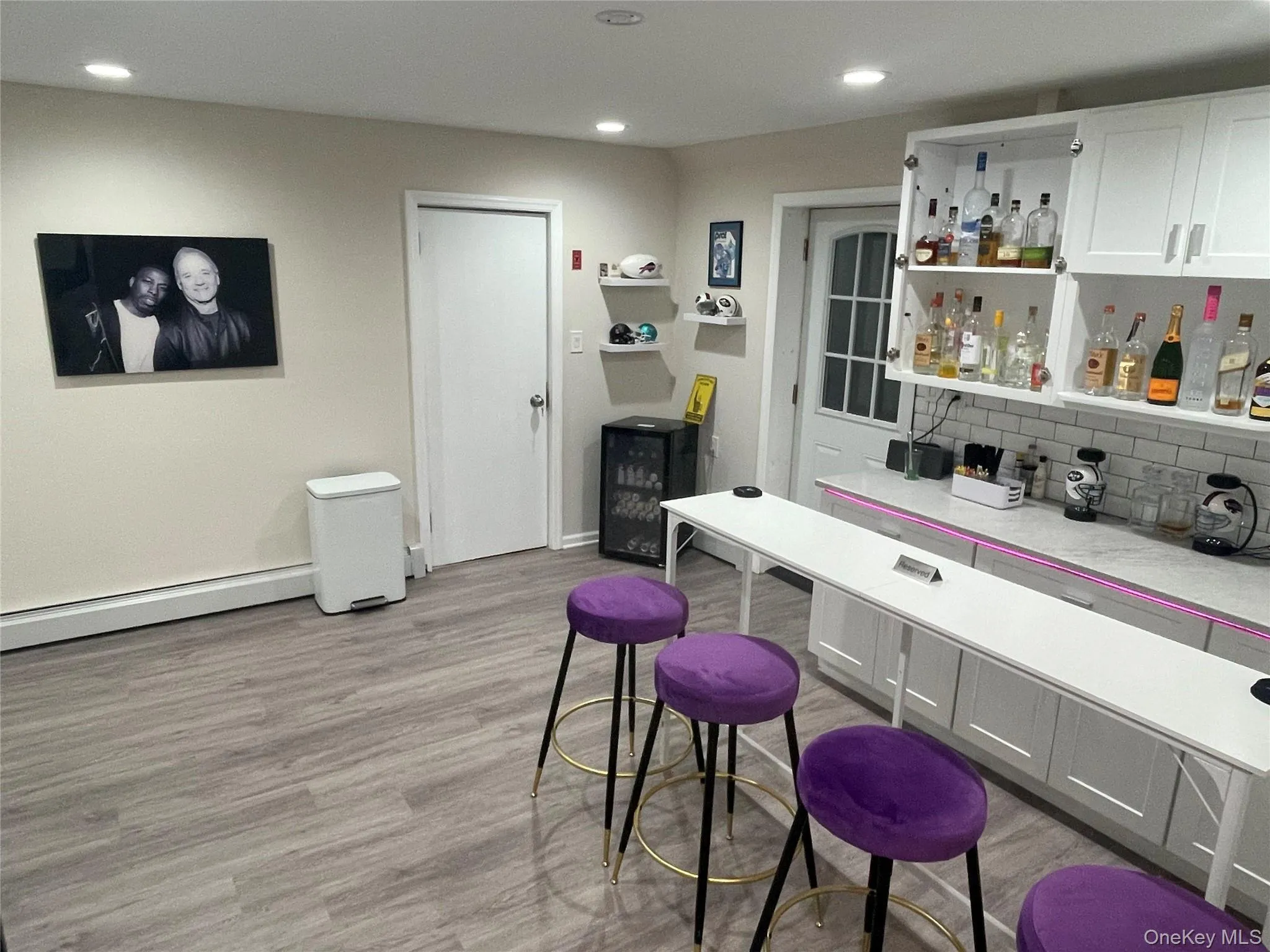 Indoor dry bar featuring baseboard heating, white cabinetry, recessed lighting, tasteful backsplash, and wine cooler Indoor dry bar featuring baseboard heating, white cabinetry, recessed lighting, tasteful backsplash, and wine cooler