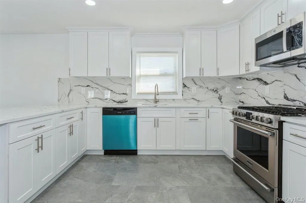 Kitchen featuring stainless steel appliances, white cabinetry, light stone countertops, ornamental molding, and recessed lighting Kitchen featuring stainless steel appliances, white cabinetry, light stone countertops, ornamental molding, and recessed lighting