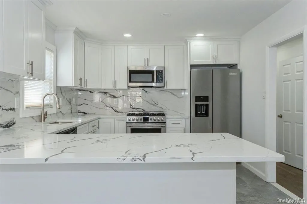 Kitchen featuring light stone countertops, appliances with stainless steel finishes, white cabinets, decorative backsplash, and recessed lighting Kitchen featuring light stone countertops, appliances with stainless steel finishes, white cabinets, decorative backsplash, and recessed lighting