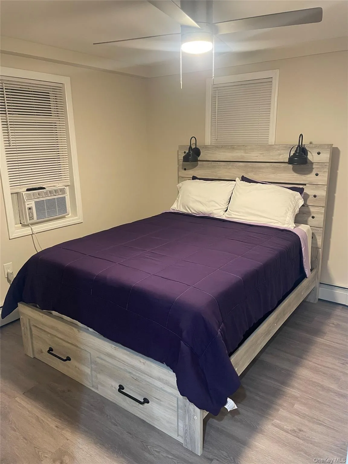 Bedroom with ceiling fan, wood finished floors, baseboard heating, and cooling unit Bedroom with ceiling fan, wood finished floors, baseboard heating, and cooling unit