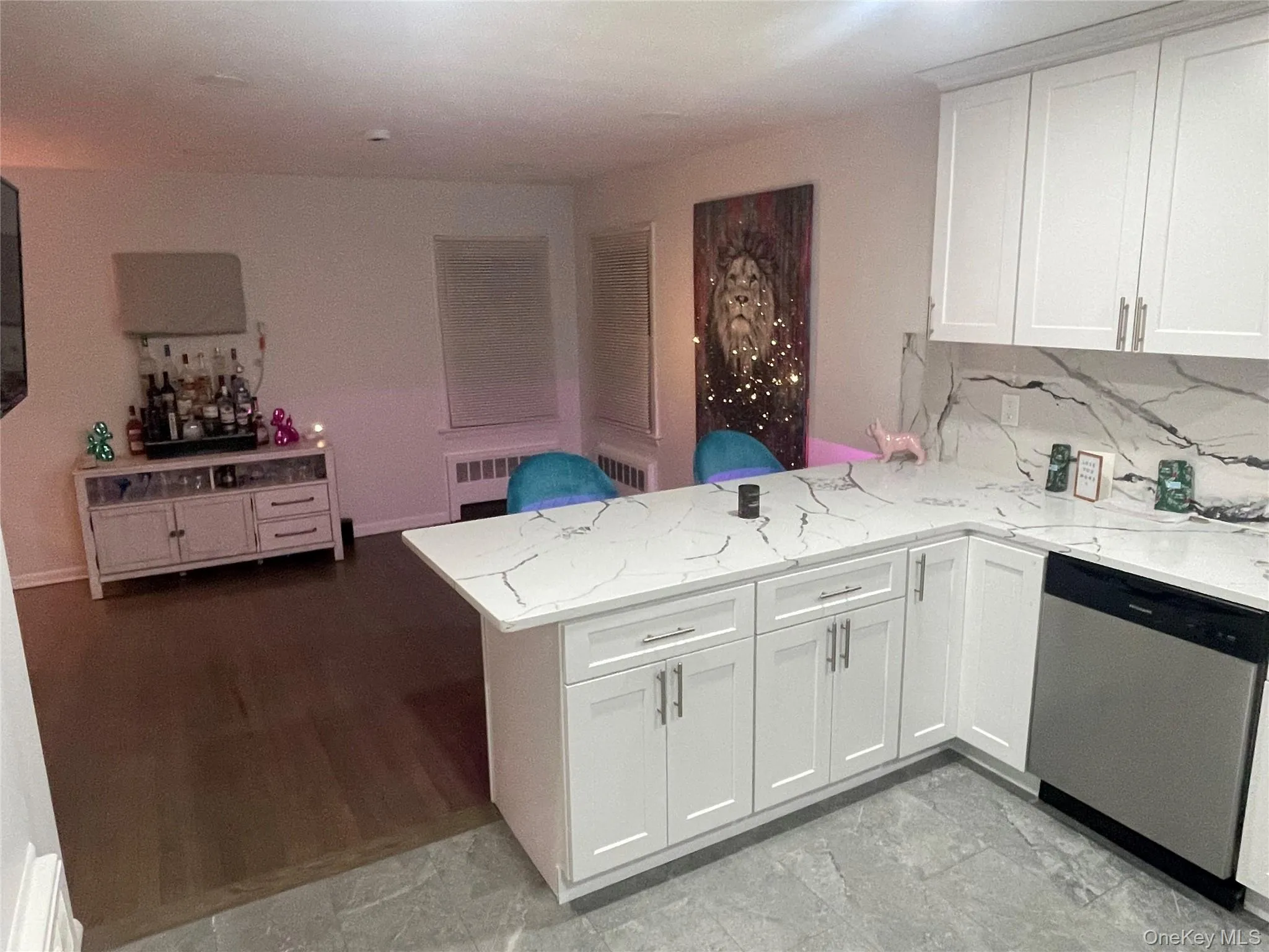 Kitchen with a peninsula, dishwasher, light stone counters, white cabinets, and decorative backsplash Kitchen with a peninsula, dishwasher, light stone counters, white cabinets, and decorative backsplash