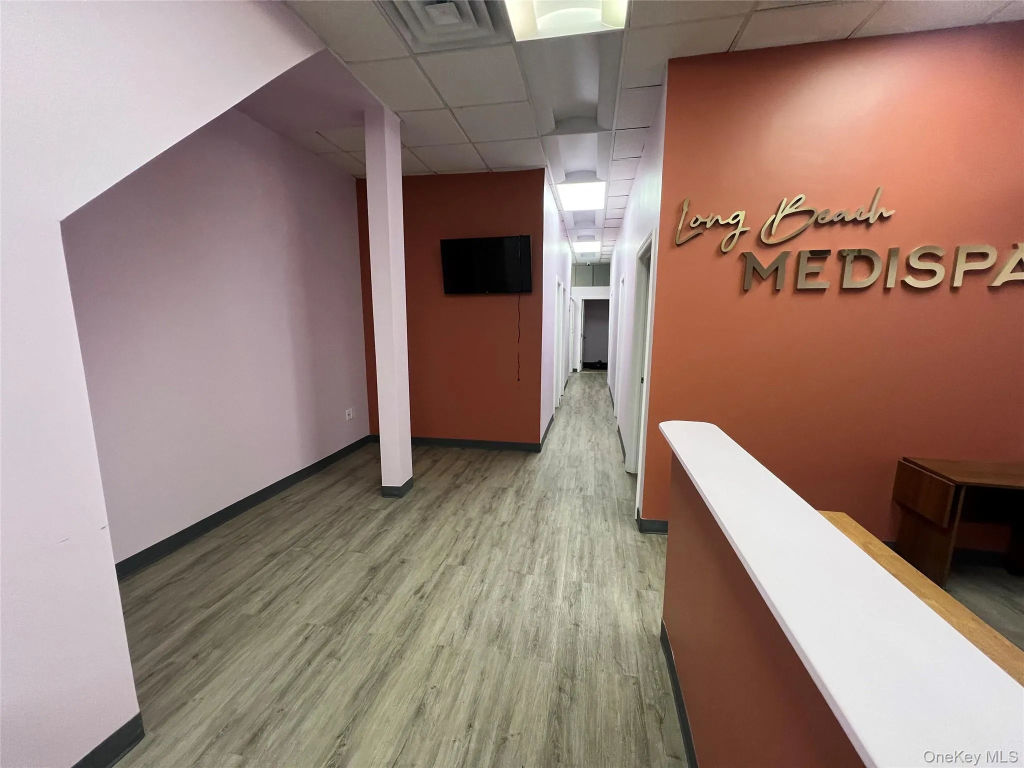 Hallway featuring a drop ceiling and wood finished floors Hallway featuring a drop ceiling and wood finished floors