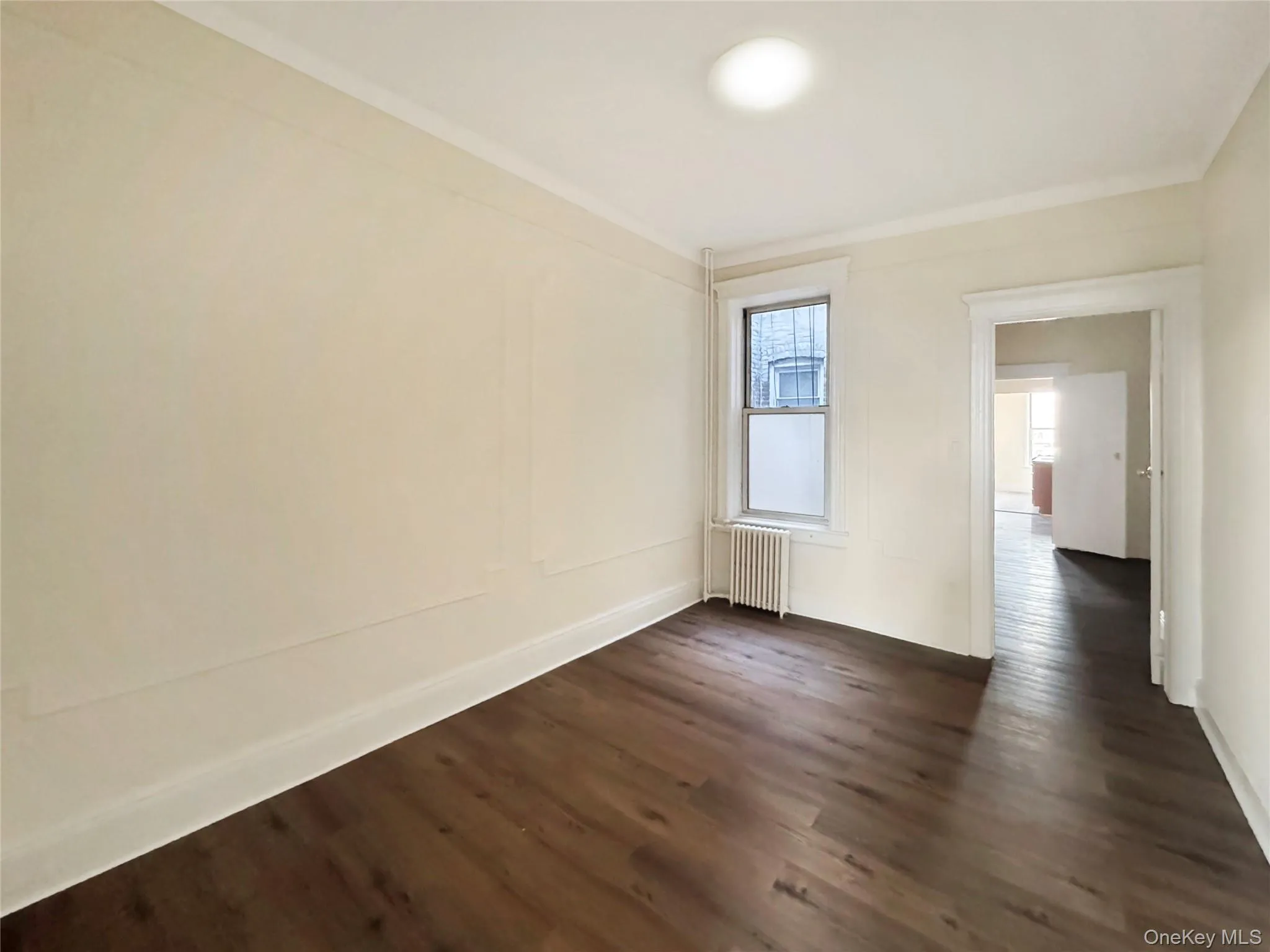 Empty room featuring dark wood-style flooring and radiator Empty room featuring dark wood-style flooring and radiator