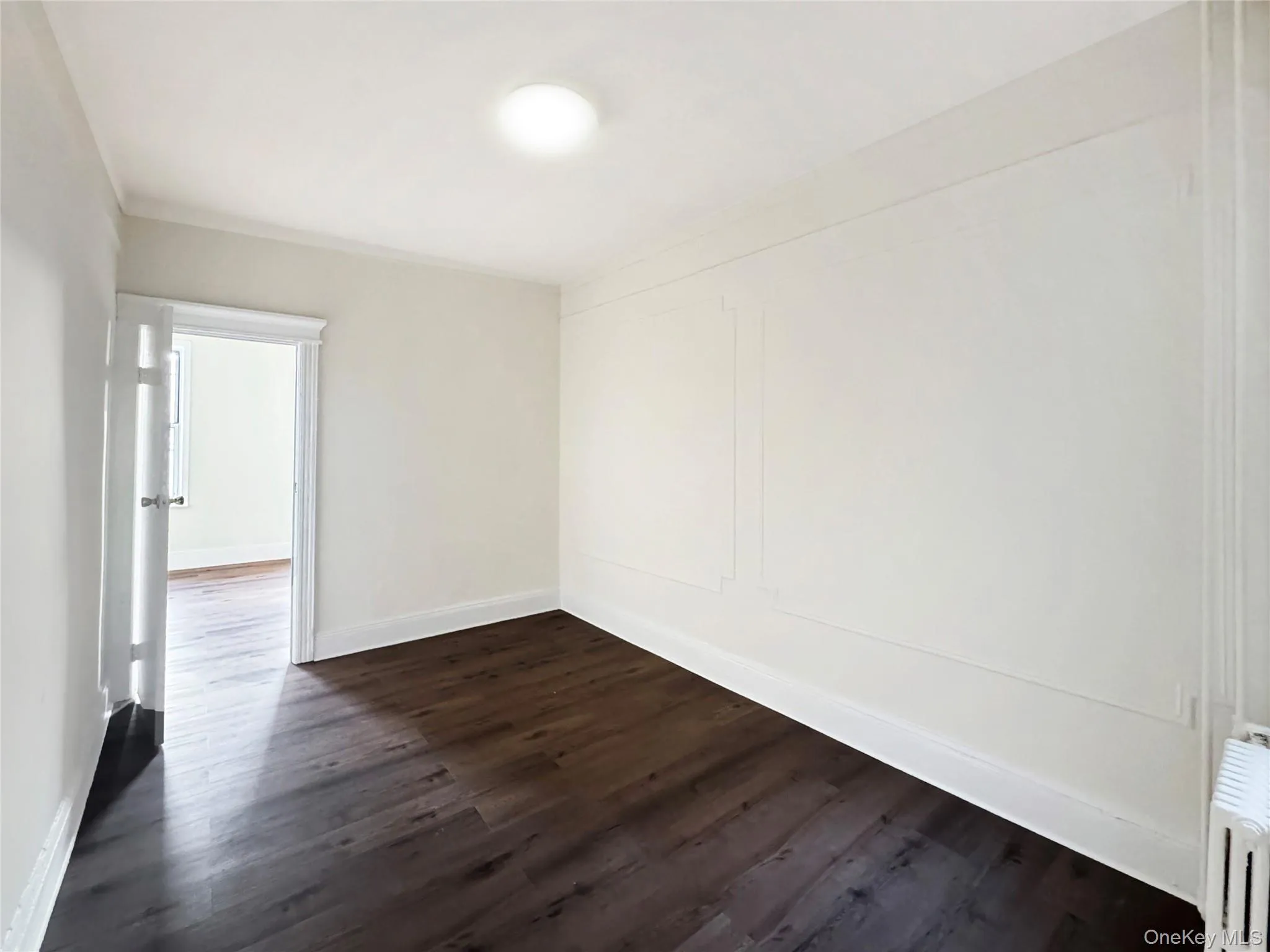 Empty room featuring dark wood finished floors and radiator Empty room featuring dark wood finished floors and radiator