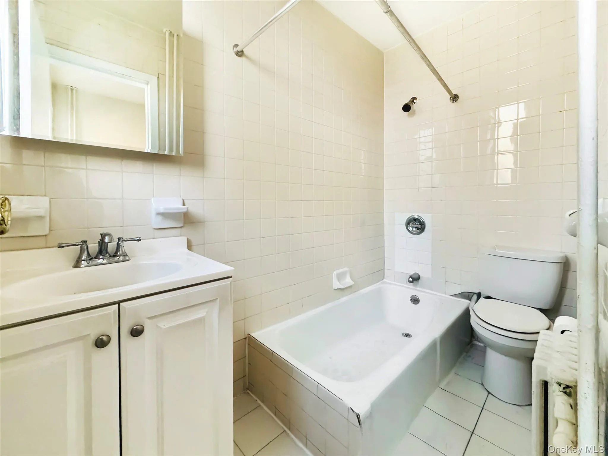 Bathroom with tile walls, vanity, shower / tub combination, light tile patterned floors, and tasteful backsplash Bathroom with tile walls, vanity, shower / tub combination, light tile patterned floors, and tasteful backsplash