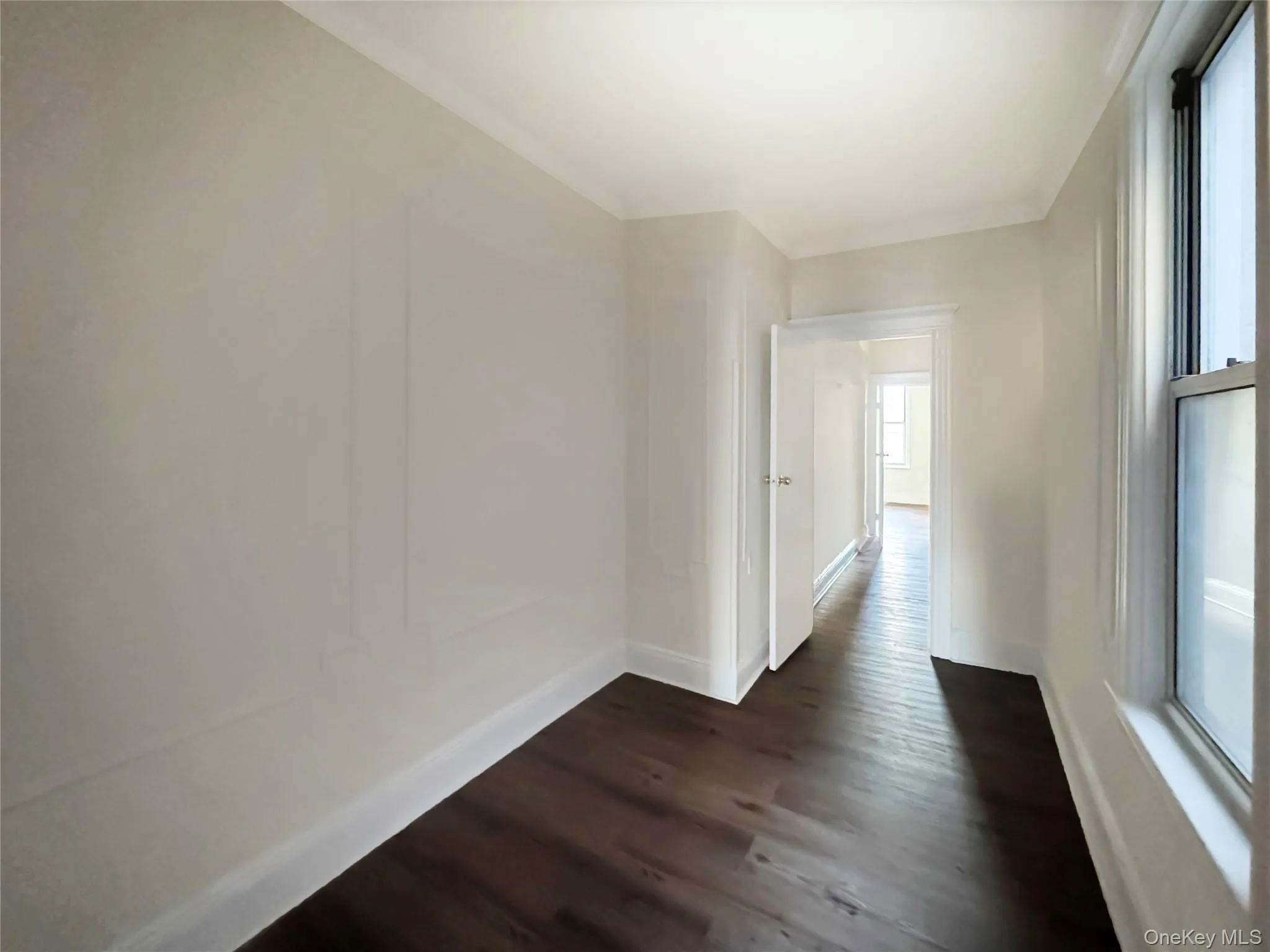 Hallway featuring dark wood-style flooring and baseboards Hallway featuring dark wood-style flooring and baseboards
