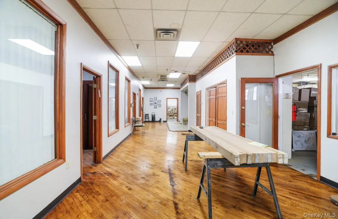 Hall with hardwood / wood-style floors, visible vents, baseboards, and a drop ceiling Hall with hardwood / wood-style floors, visible vents, baseboards, and a drop ceiling