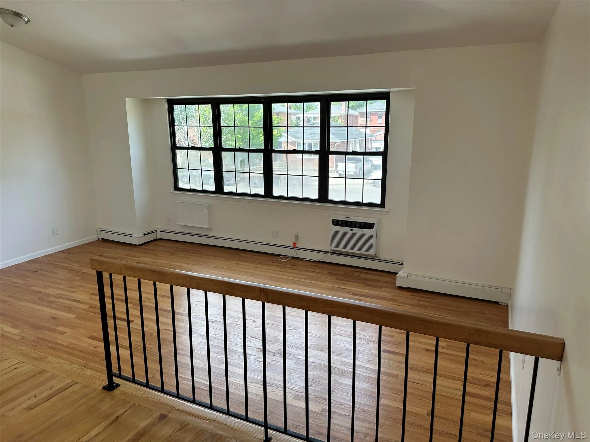 Unfurnished room featuring light wood-type flooring, a baseboard radiator, and a wall unit AC Unfurnished room featuring light wood-type flooring, a baseboard radiator, and a wall unit AC