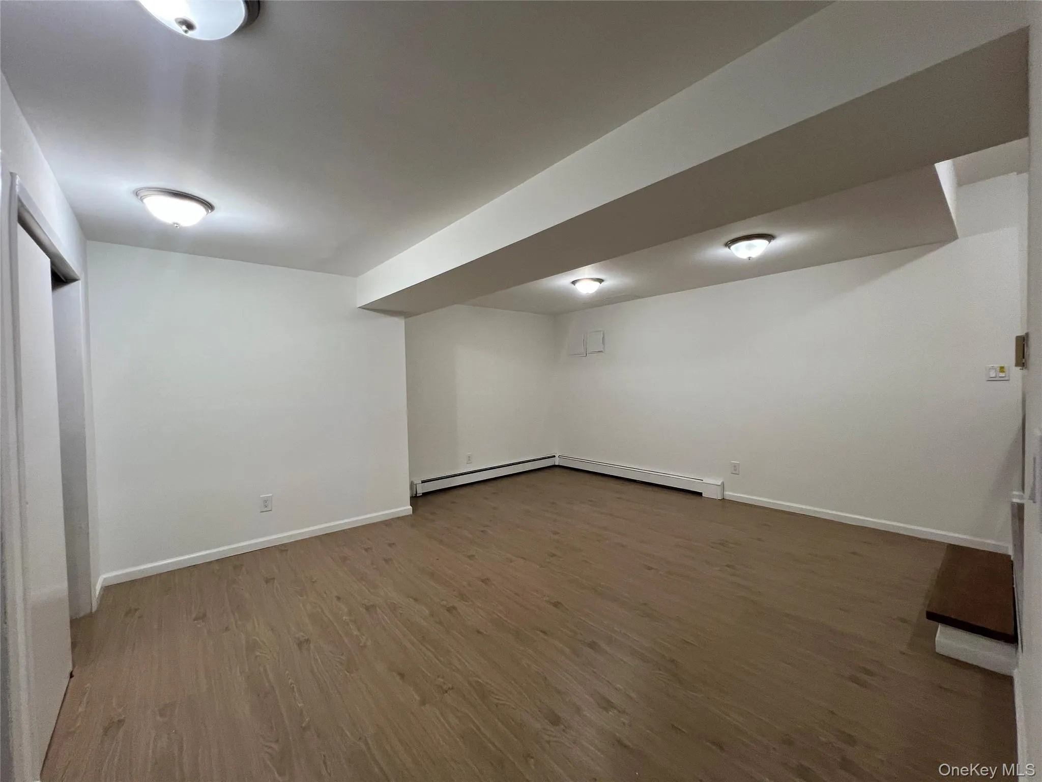 Finished below grade area featuring wood finished floors and baseboard heating Finished below grade area featuring wood finished floors and baseboard heating