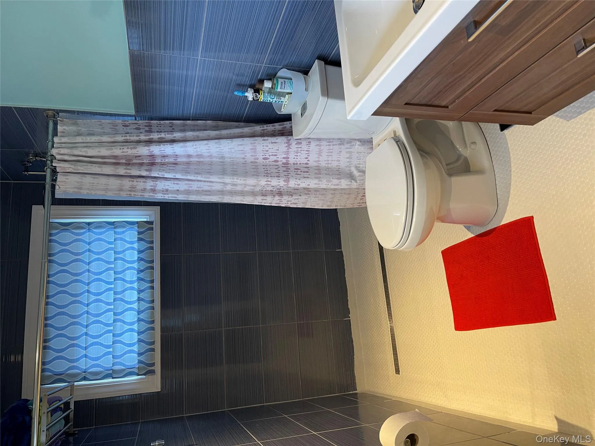 Bathroom featuring tile patterned flooring, tile walls, vanity, curtained shower, and toilet Bathroom featuring tile patterned flooring, tile walls, vanity, curtained shower, and toilet