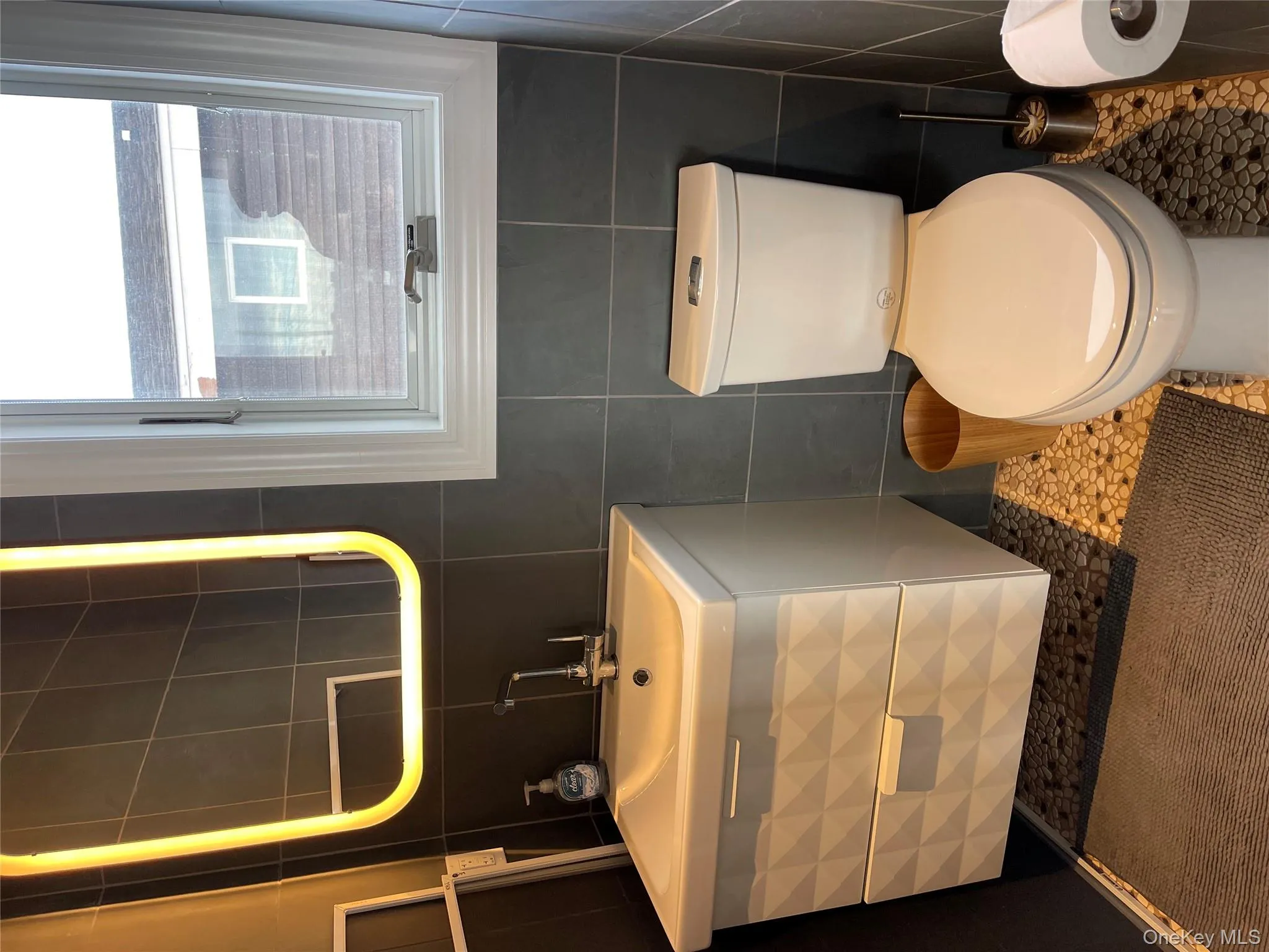 Bathroom with vanity, tile patterned flooring, tile walls, and toilet Bathroom with vanity, tile patterned flooring, tile walls, and toilet